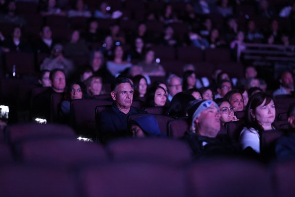 A packed theater audience watches intently in the dark during a People of the West screening.